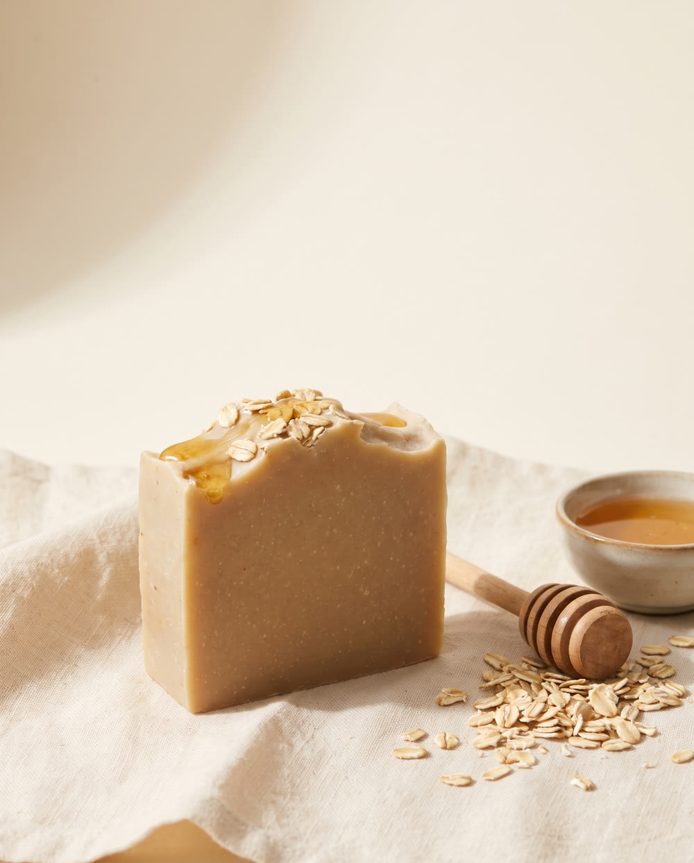 Oat and Honey bar flecked with rolled oats beside a honey dipper